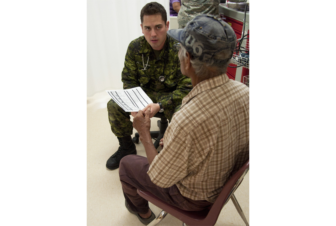 A Canadian armed forces member helping with medical treatment