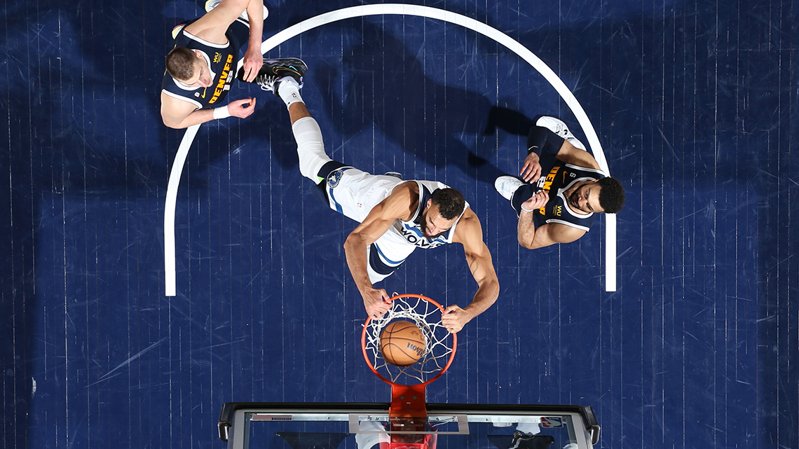 Rudy Gobert, #27 of the Minnesota Timberwolves (2023), dunks the basketball into the net, while two nearby opposing players look on.