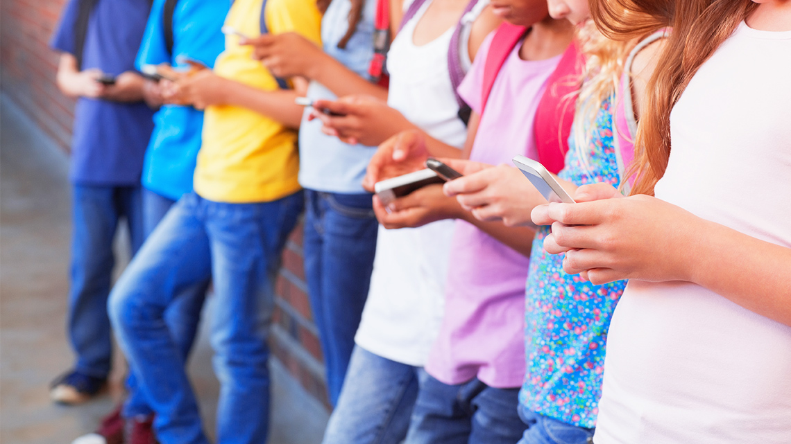 Children focusing on their cellphones at school.