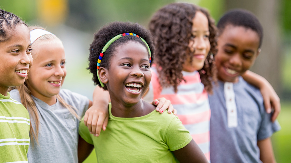 Children standing in a line with their arms over each other’s shoulders.