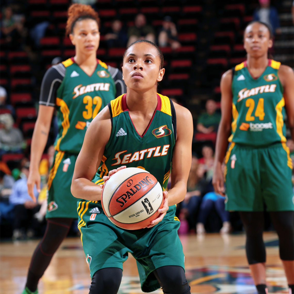 Angel Goodrich, #3 of the Seattle Storm crouches to throw the basketball, while two other team players look on.