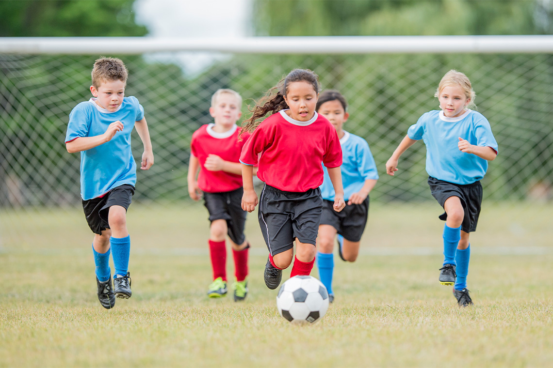 Children playing soccer on an outdoor field.