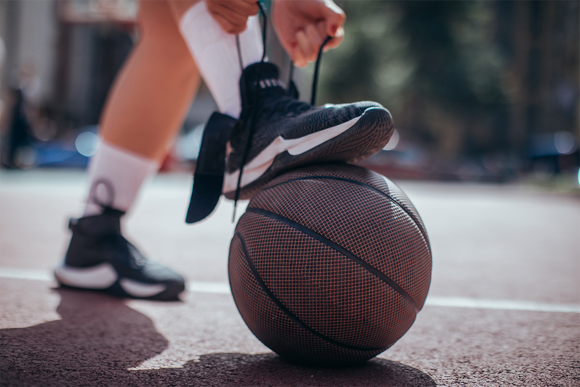 Basketball player tying laces on their shoe.