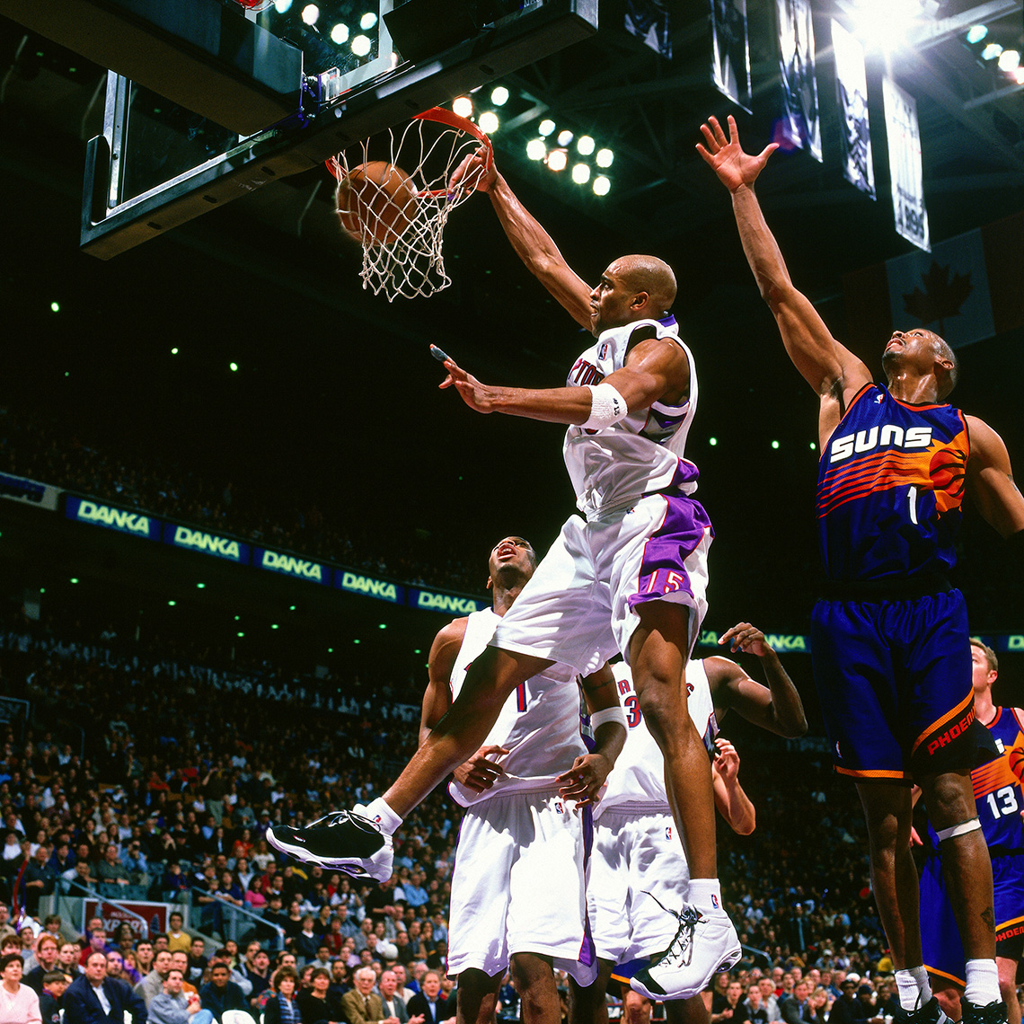 Vince Carter dunks the basketball as Anfernee Hardaway stretches his arm out to defend. Other team players look on.
