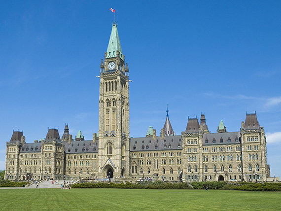A giant castle-like stone building with pointed arches, tall spires, and ornate carvings. In the middle is a soaring clock tower.